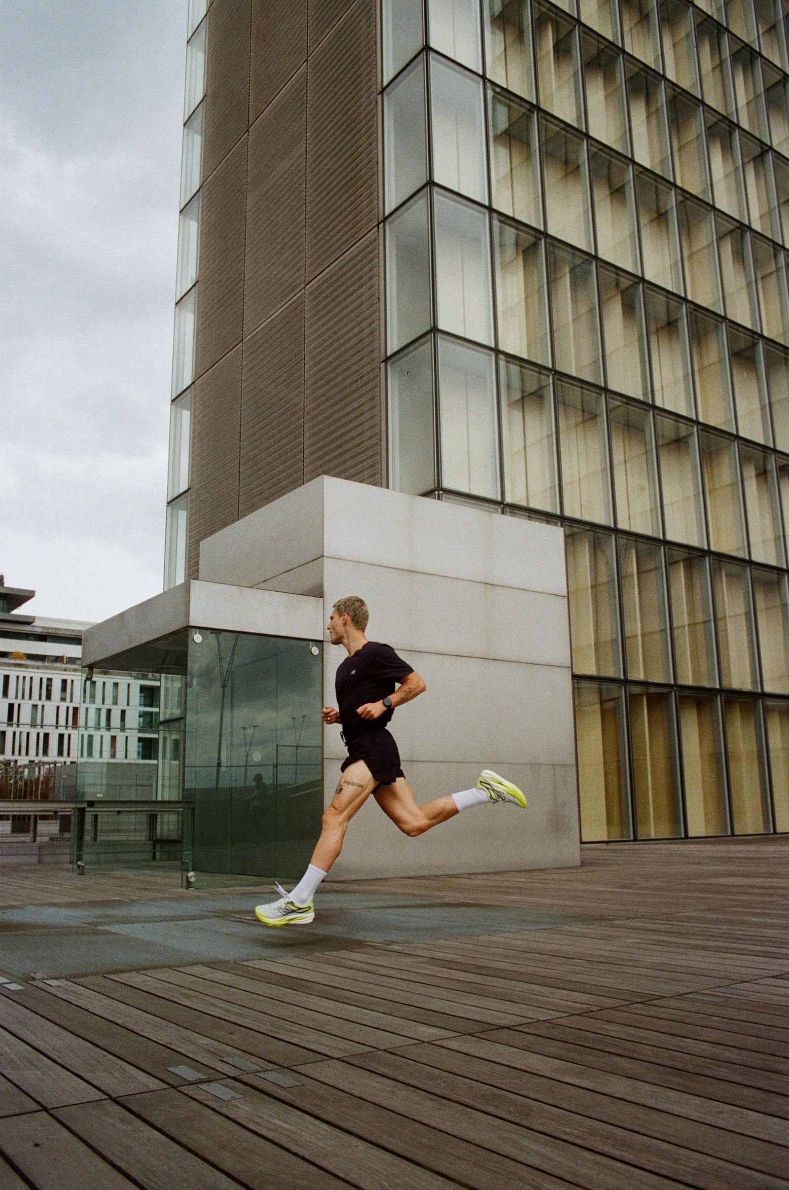 Coureur en foulée devant un immeuble de verre