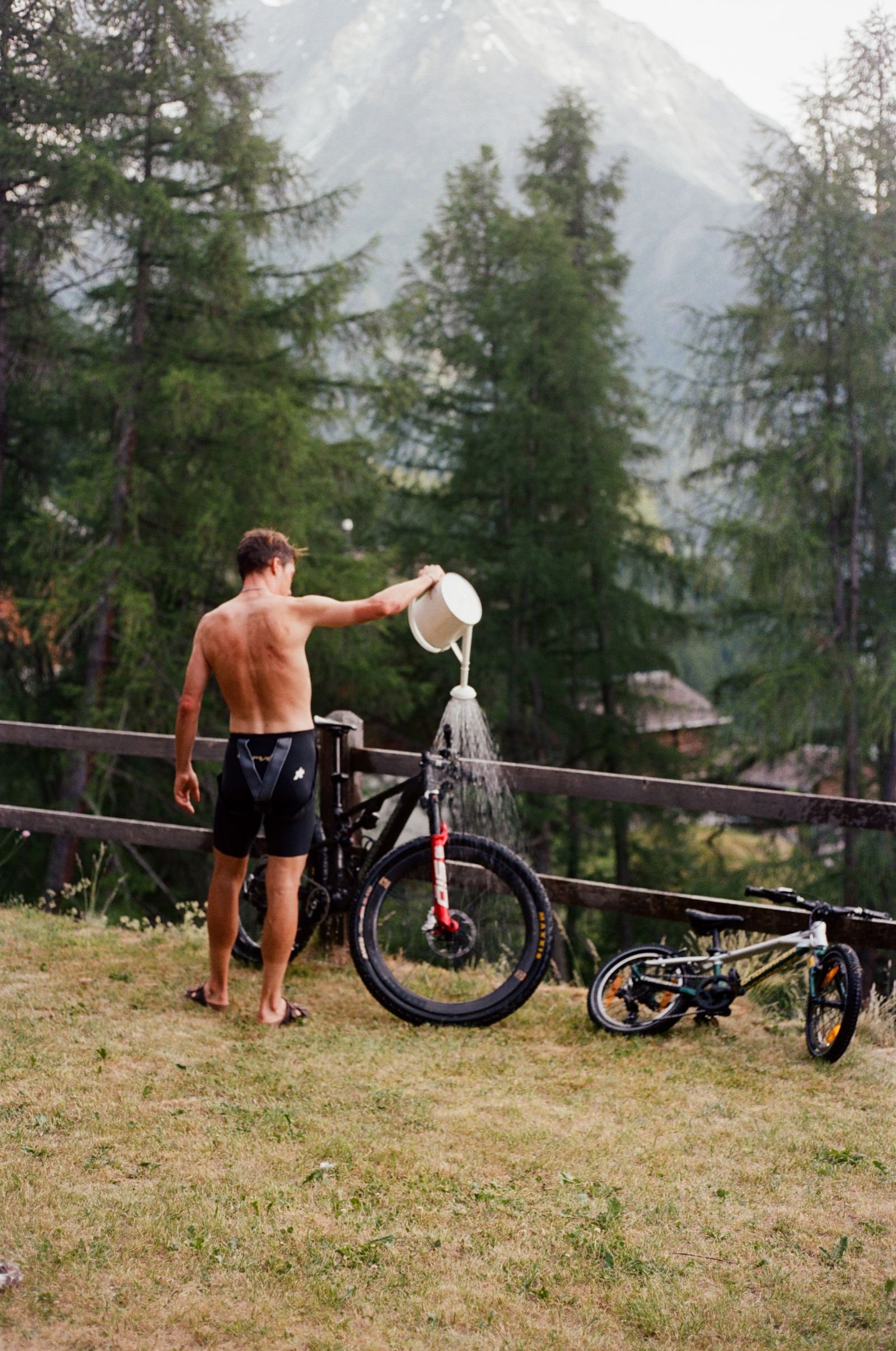 Coureur nettoyant son vélo à l'arrosoir devant la montagne