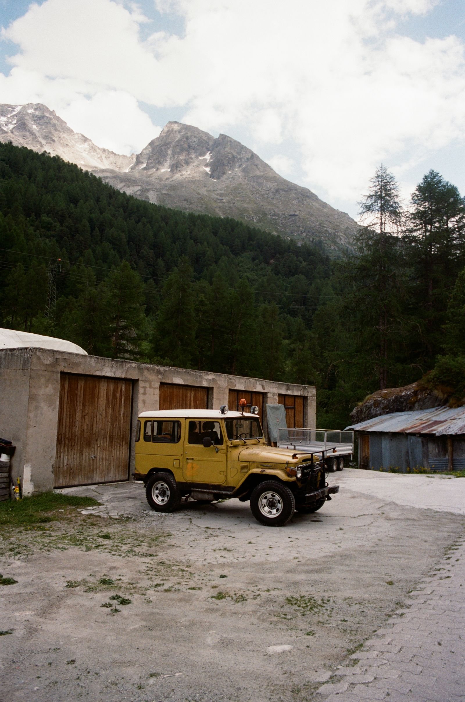 Land Cruiser jaune devant des garages de village